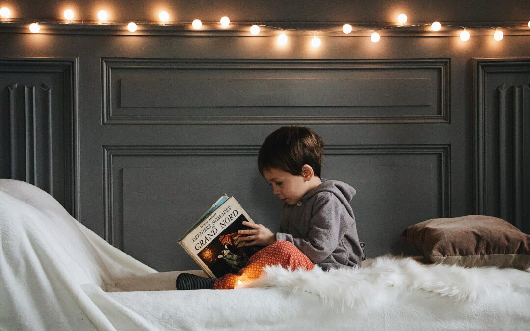 Poika lukee kirjaa sängyllä.