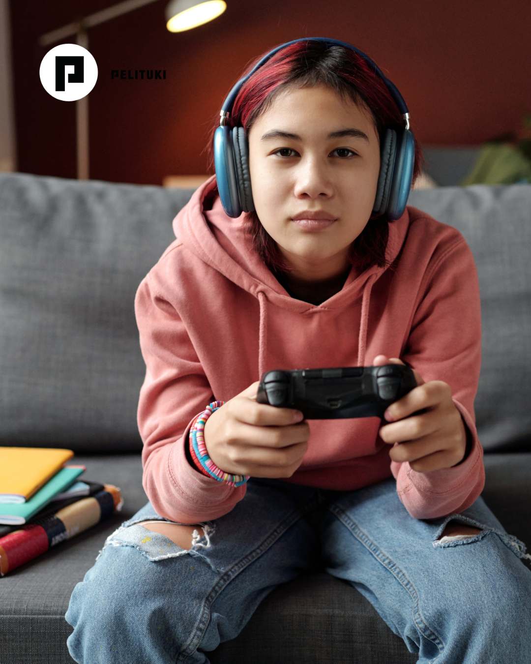 Pieni tyttö lepää sohvalla ja pitelee kädessään korkealla älypuhelinta, jota kohti hän katsoo iloisena